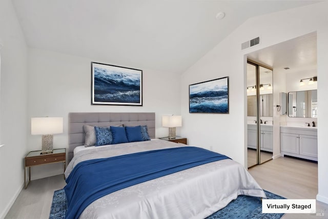 bedroom with visible vents, vaulted ceiling, a sink, and light wood finished floors