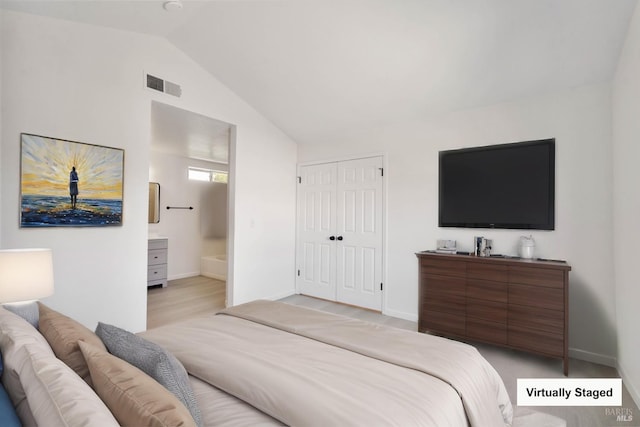 bedroom featuring baseboards, visible vents, lofted ceiling, and ensuite bath