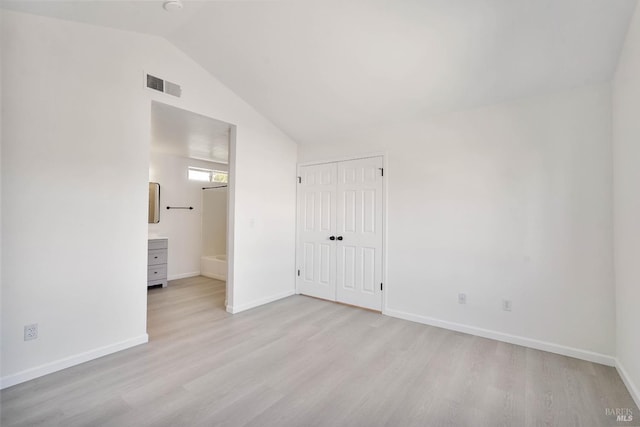 unfurnished bedroom with light wood-style flooring, baseboards, vaulted ceiling, visible vents, and a closet