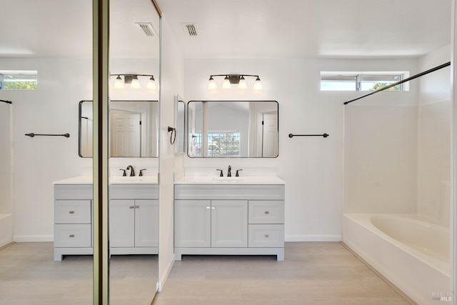 bathroom with vanity, baseboards, wood finished floors, and visible vents