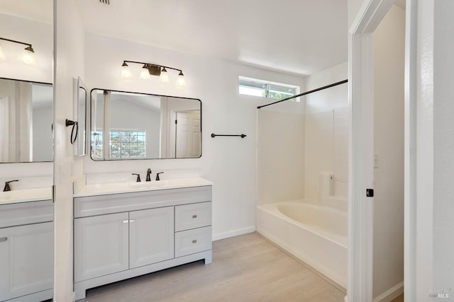bathroom featuring baseboards, shower / washtub combination, wood finished floors, and vanity