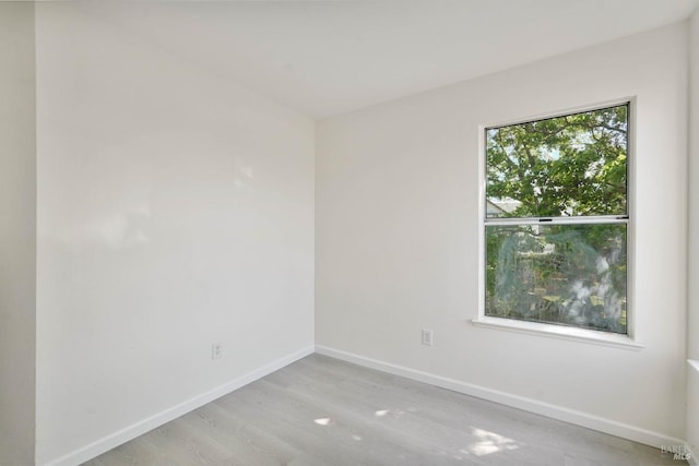 spare room with baseboards and wood finished floors