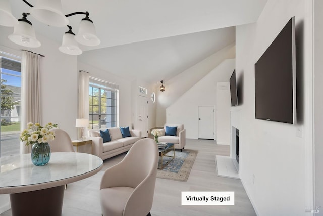 dining space featuring a fireplace, vaulted ceiling, and light wood-type flooring