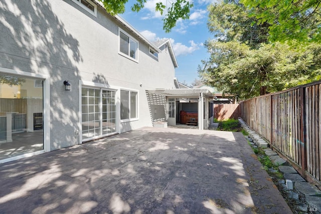 exterior space with a pergola, a patio, a fenced backyard, stucco siding, and a hot tub