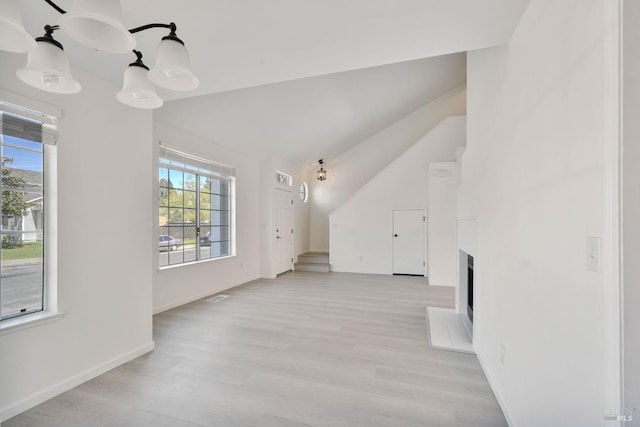 additional living space featuring a fireplace with raised hearth, baseboards, lofted ceiling, light wood-type flooring, and visible vents