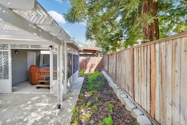 view of yard with a fenced backyard, a sunroom, a hot tub, and a patio area