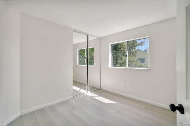 unfurnished bedroom featuring a closet, baseboards, and light wood-style floors