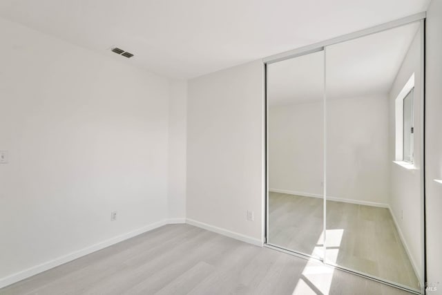 unfurnished bedroom with visible vents, baseboards, a closet, and light wood-type flooring