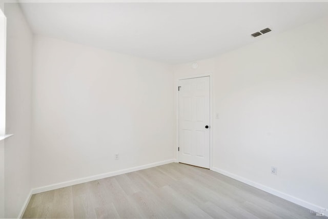 spare room with baseboards, visible vents, and wood finished floors