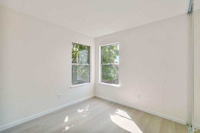 spare room with baseboards and light wood-style floors