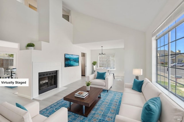 living area with high vaulted ceiling, baseboards, a fireplace with raised hearth, and wood finished floors