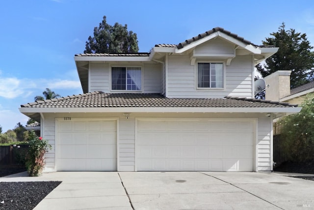 traditional-style home featuring a garage, a tiled roof, and concrete driveway