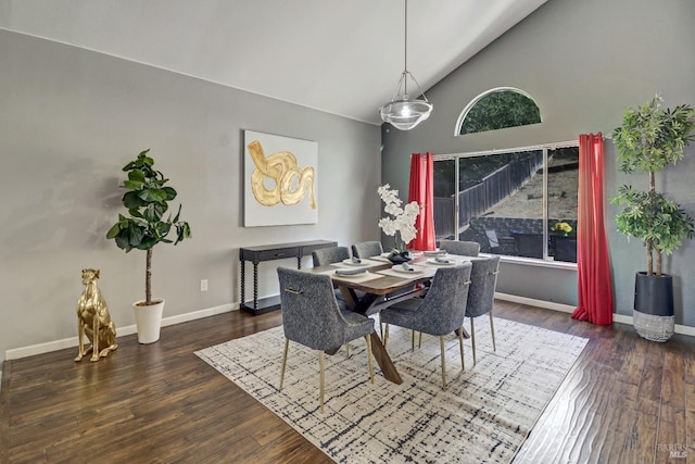 dining space featuring baseboards, wood finished floors, and high vaulted ceiling