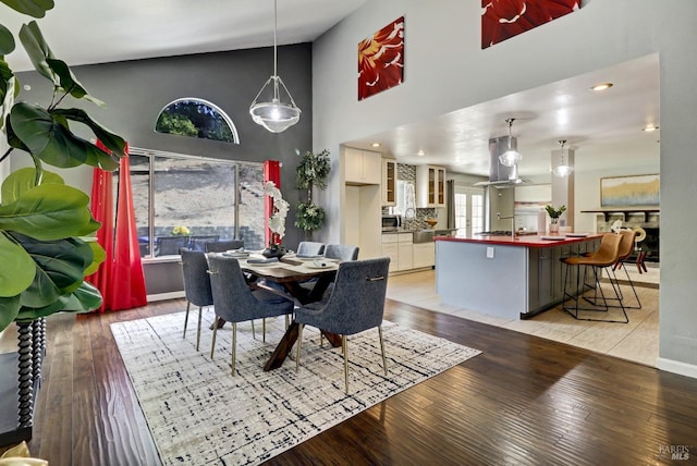 dining room with high vaulted ceiling and light wood finished floors