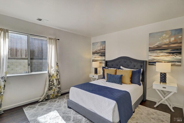 bedroom with baseboards, visible vents, and wood finished floors