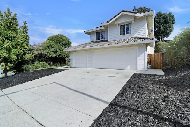 exterior space featuring driveway, fence, a tile roof, and a garage