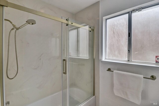 bathroom featuring plenty of natural light and combined bath / shower with glass door
