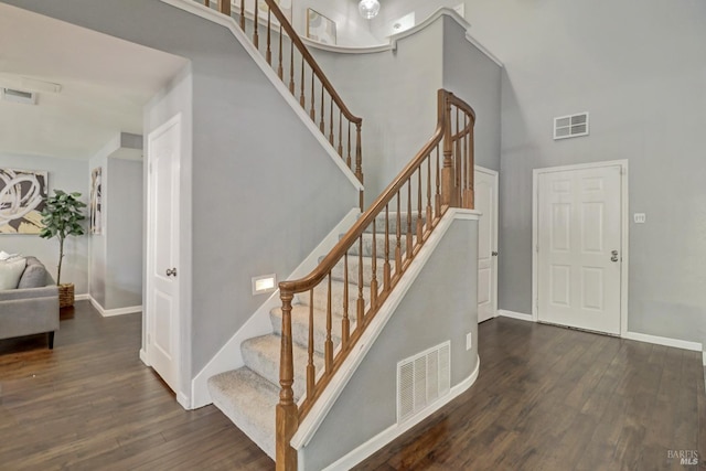 stairs with a high ceiling, wood finished floors, and visible vents