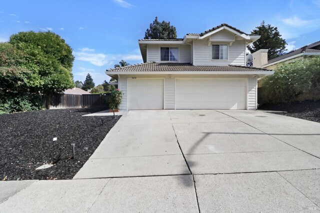 view of front of home featuring a garage, fence, a tile roof, and concrete driveway