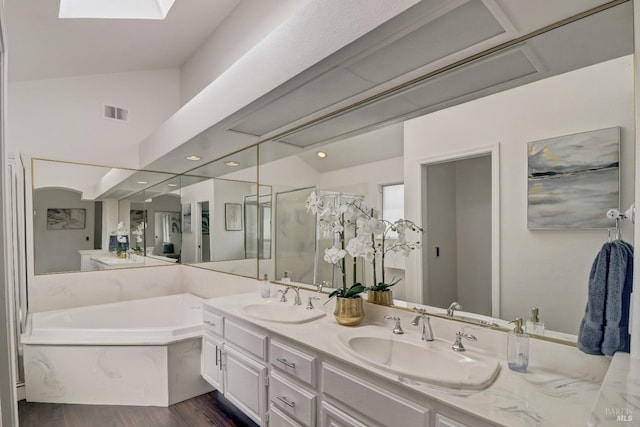 full bath featuring wood finished floors, a sink, a garden tub, and a stall shower