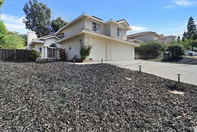 view of side of home featuring fence, an attached garage, a chimney, and driveway