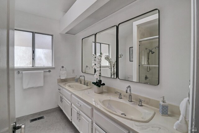 full bath with a sink, a shower stall, double vanity, and visible vents