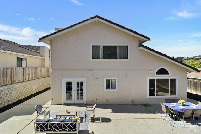 rear view of property featuring a fenced backyard, a patio area, stucco siding, and french doors