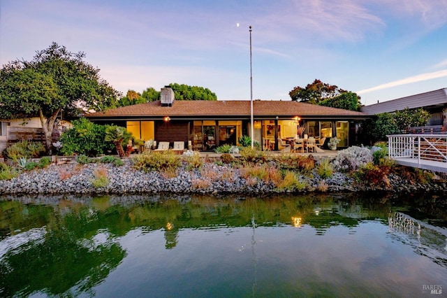 rear view of property featuring a water view and a chimney