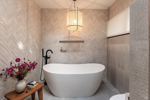 full bathroom featuring an inviting chandelier, tile walls, tile patterned flooring, and a soaking tub