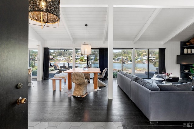 living area featuring a wealth of natural light, vaulted ceiling with beams, a water view, and a notable chandelier