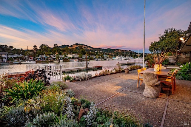 patio terrace at dusk with outdoor dining area and a water and mountain view