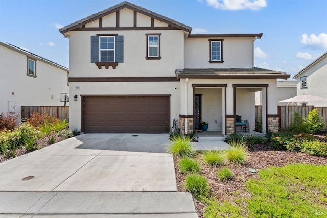 view of front facade with fence, a garage, stucco siding, concrete driveway, and covered porch