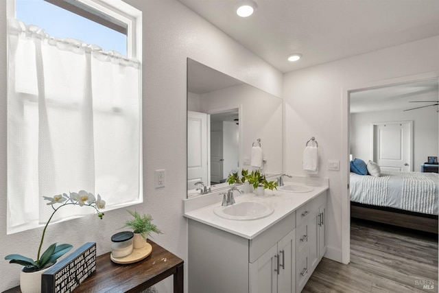 ensuite bathroom featuring connected bathroom, double vanity, a sink, and wood finished floors