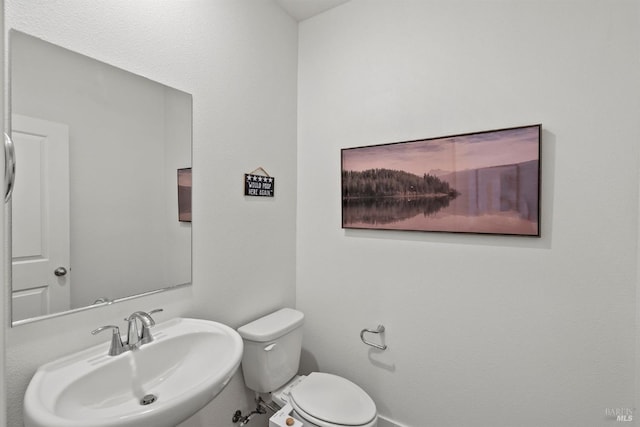 half bath featuring a sink, baseboards, and toilet