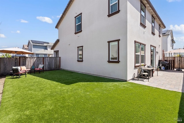 rear view of property with a patio, a fenced backyard, a lawn, and stucco siding