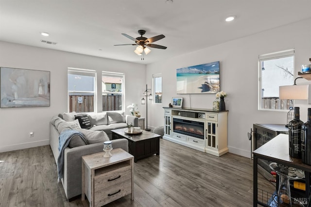 living room with baseboards, ceiling fan, and a wealth of natural light
