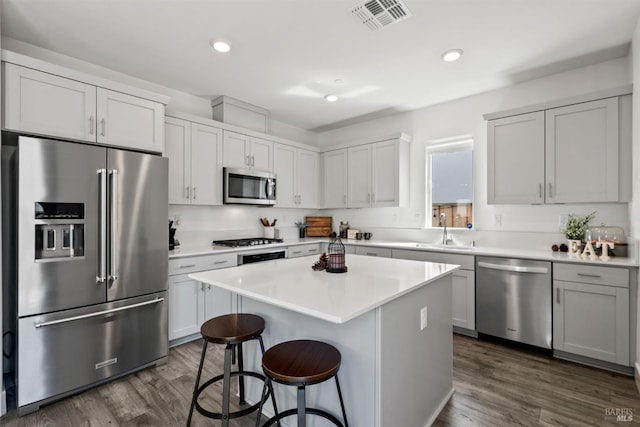 kitchen featuring dark wood-style flooring, stainless steel appliances, visible vents, and a breakfast bar