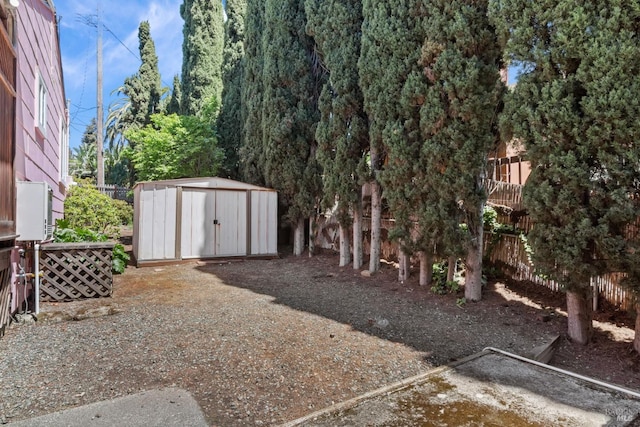 view of yard featuring a storage shed, fence, and an outbuilding