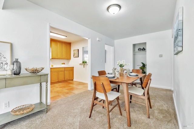 dining space featuring baseboards, light tile patterned floors, and light carpet