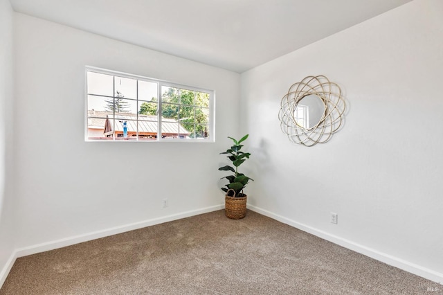 carpeted spare room featuring baseboards