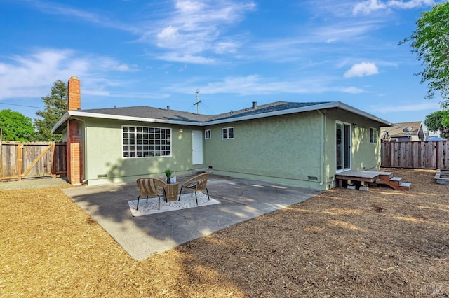 rear view of property with a chimney, a fenced backyard, a patio area, and stucco siding