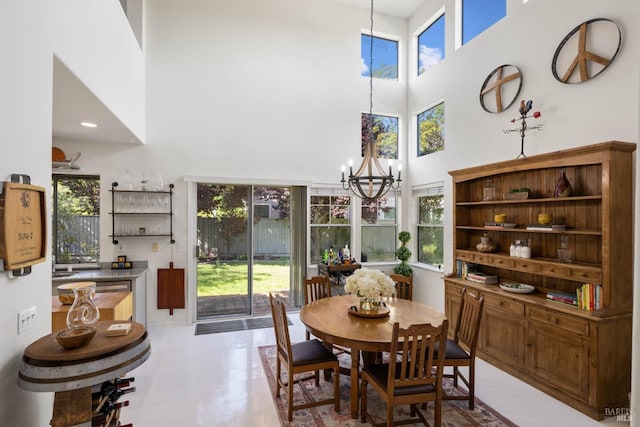 dining space with plenty of natural light, a towering ceiling, and a notable chandelier