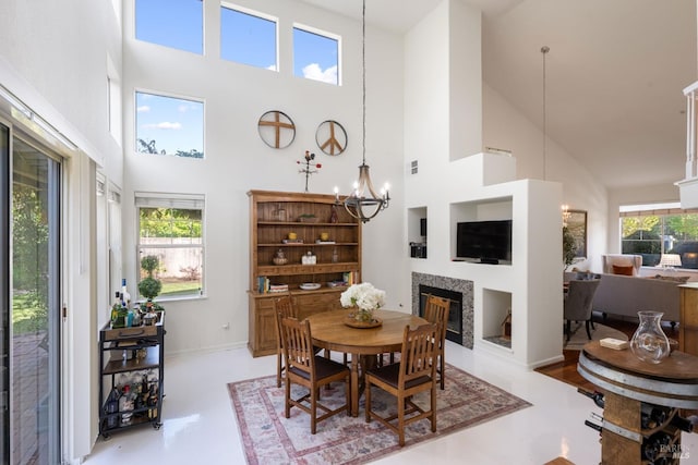 dining space with high vaulted ceiling, an inviting chandelier, a glass covered fireplace, and visible vents