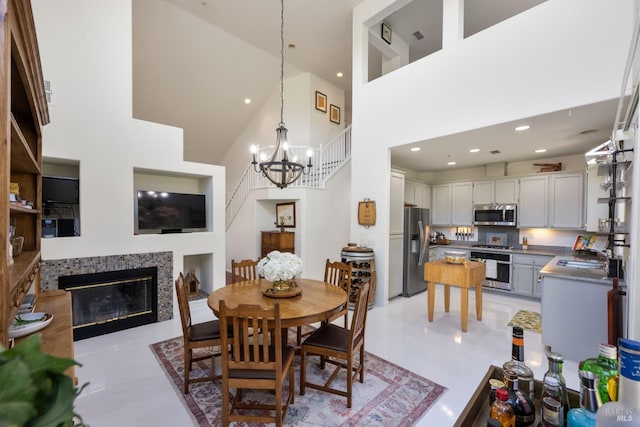 dining space featuring recessed lighting, a high ceiling, a chandelier, and a tile fireplace
