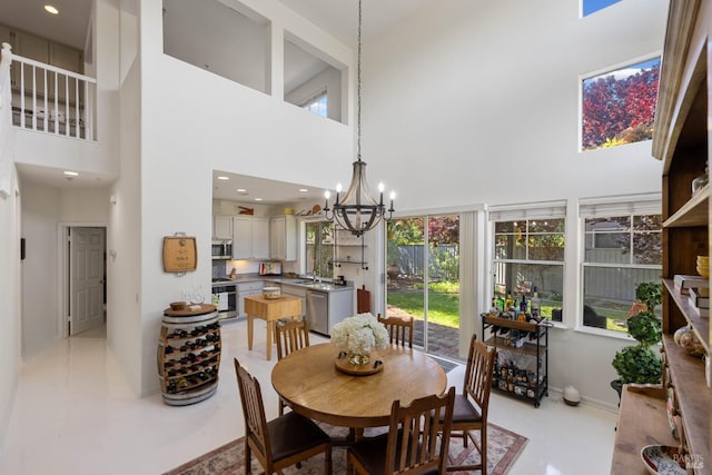 dining space with baseboards, a towering ceiling, a notable chandelier, and a wealth of natural light