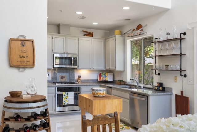 kitchen with open shelves, decorative backsplash, recessed lighting, a sink, and stainless steel appliances