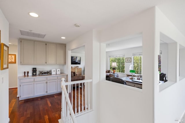 hall with recessed lighting, visible vents, an upstairs landing, and dark wood-type flooring