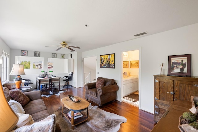 living area with a ceiling fan, visible vents, and wood finished floors