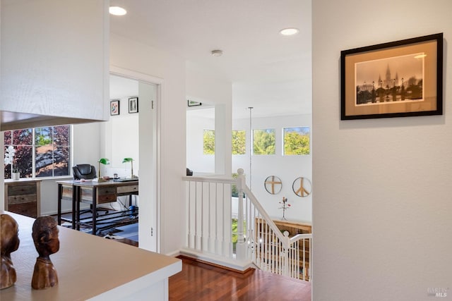 hallway with recessed lighting, wood finished floors, and an upstairs landing