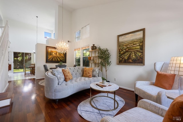 living area with a high ceiling, a chandelier, baseboards, and wood finished floors
